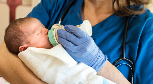 nurse bottle feeding a baby