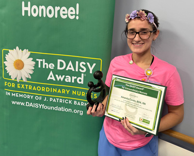 awardee wearing a headband of daisies, daisy award statue, and certificate.