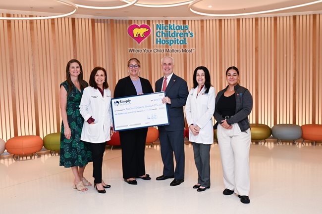 Nickalus Childen's Hospital team accepting check from Simply Healthcare team