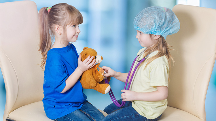 dos niñas jugando al doctor con un osito