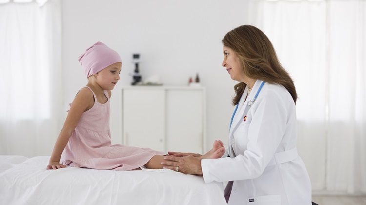 Female doctor examining the leg of a young girl with cancer.