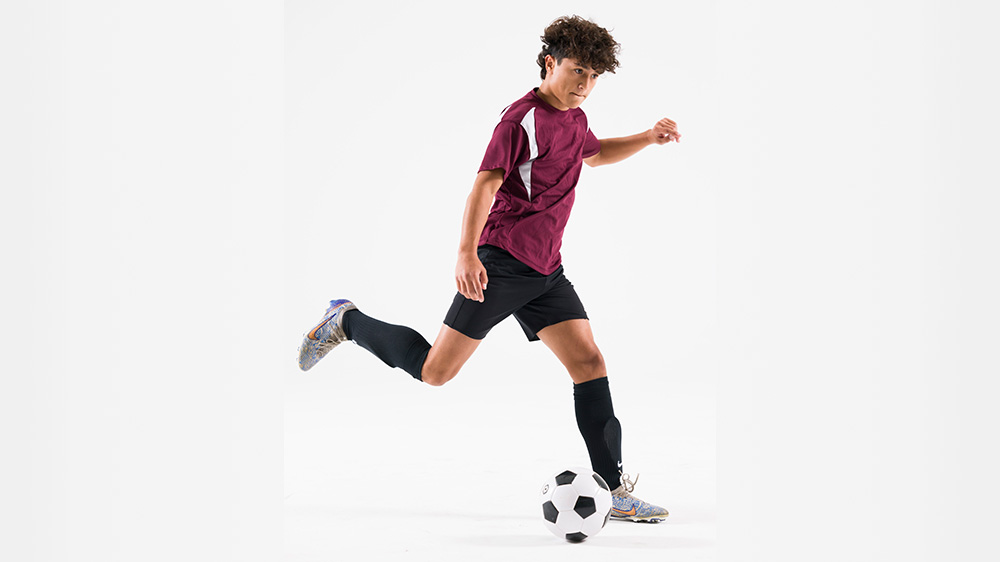 teenage boy about to kick a soccer ball.