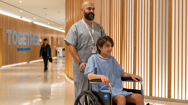 asistente médico lleva a un paciente a cirugía en una silla de ruedas.