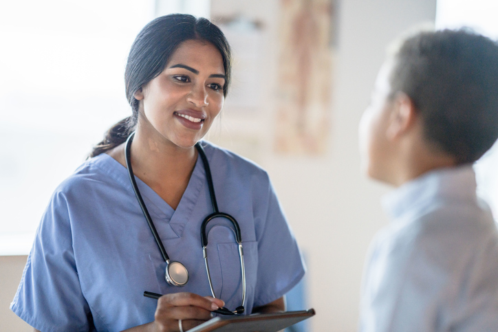 female nurse with a checklist talking to child patient.