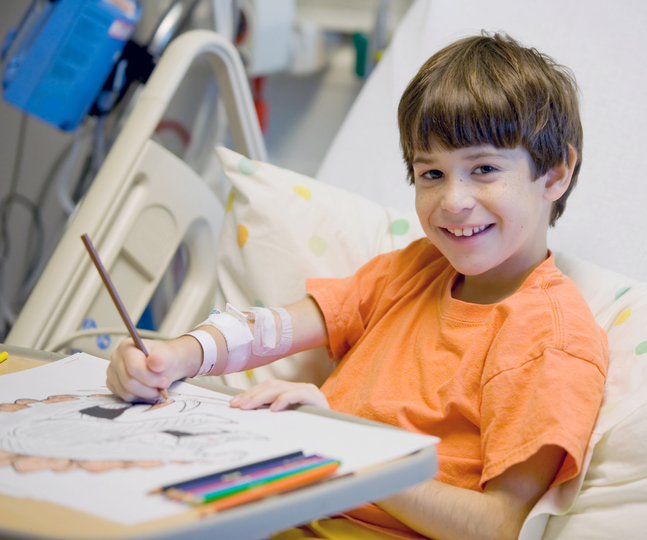 boy doodling while sitting on hospital bed.