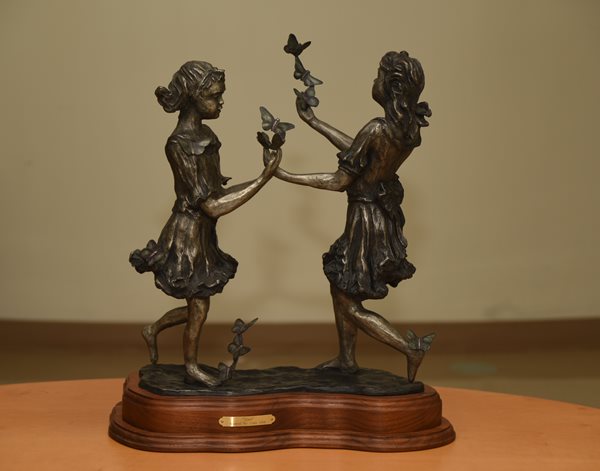 Small sculpture of two girls playing with butterflies.
